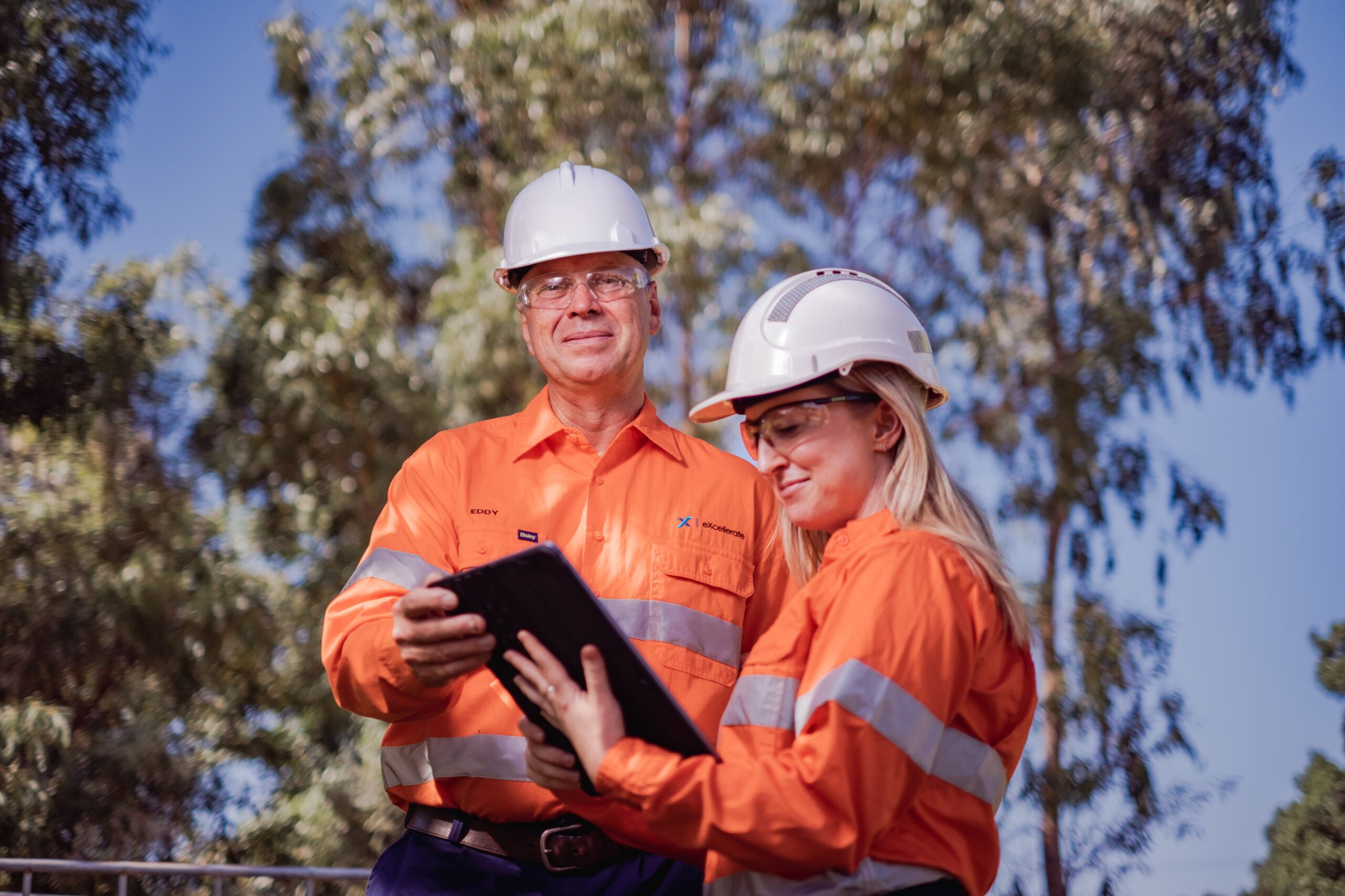 Mining supervisor and mining operator looking at tablet outside.